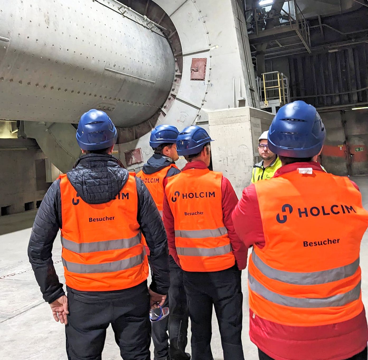 ROTEC-Team mit orangenen Sicherheitswesten in der Produktionshalle von Holcim während der Werksführung