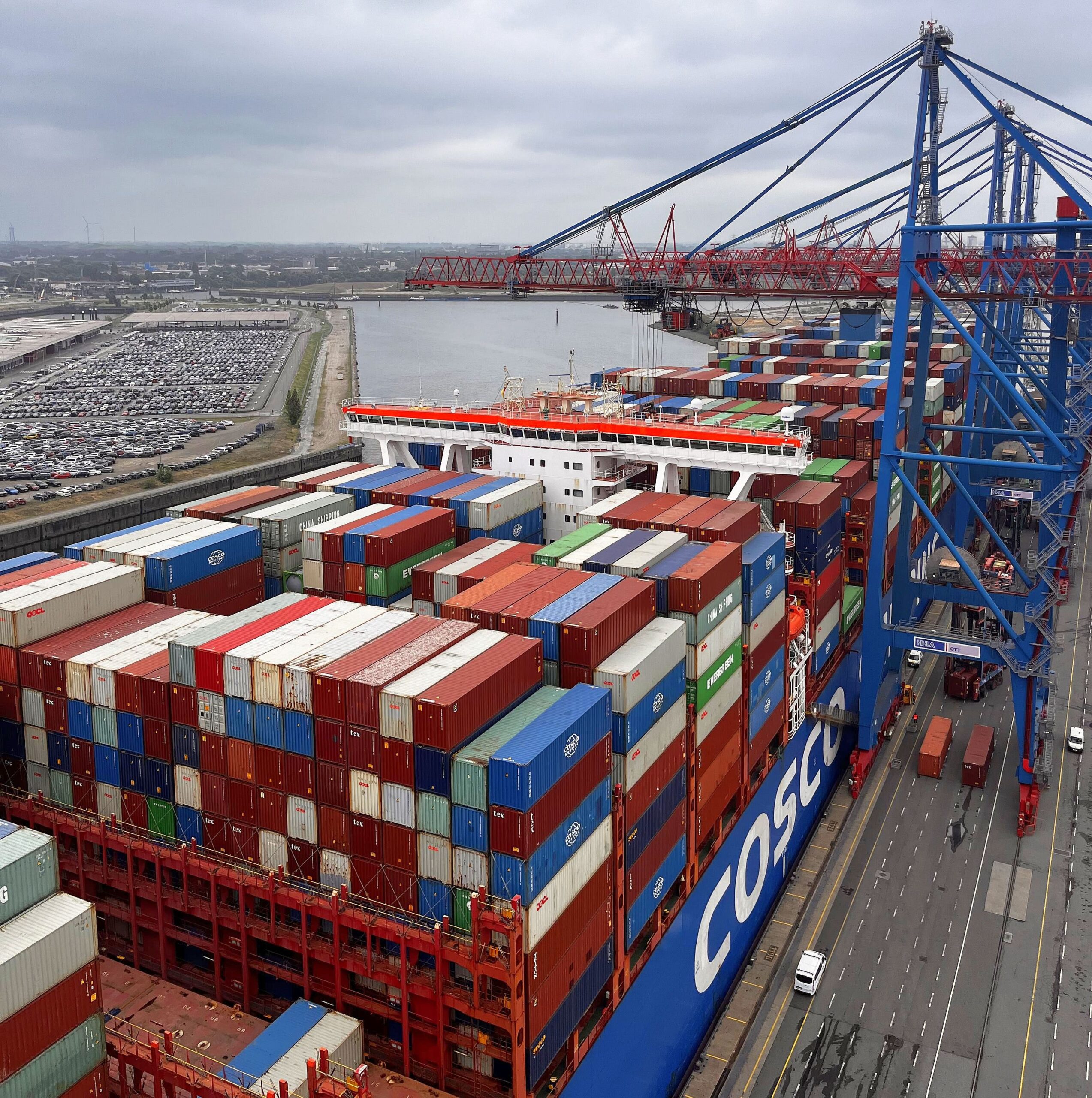 Containerschiff mit gestapelten Frachtcontainern unter großen Containerkränen im Hamburger Hafen.