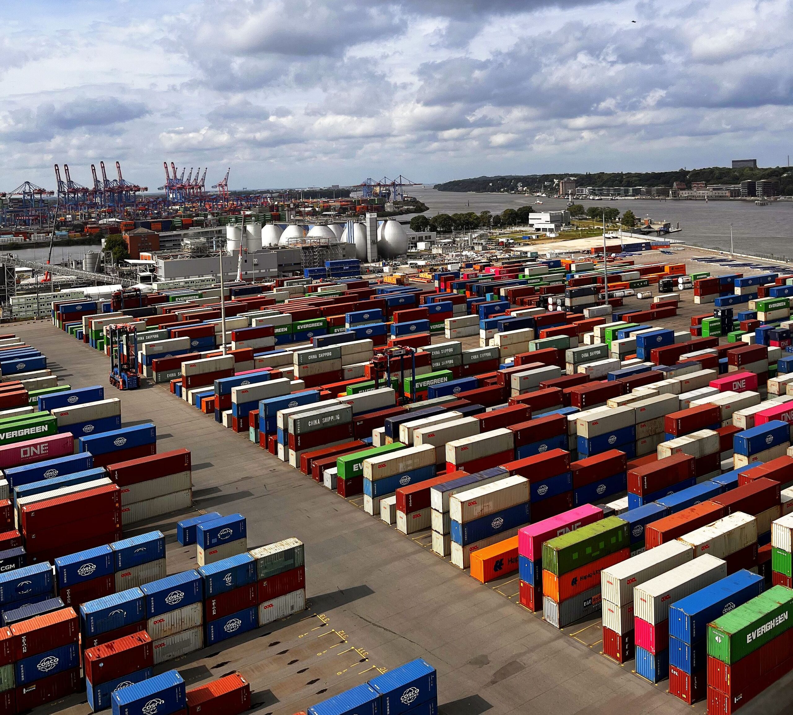 Blick über zahlreiche gestapelte Frachtcontainer und Hafenkräne am Hamburger Containerterminal.
